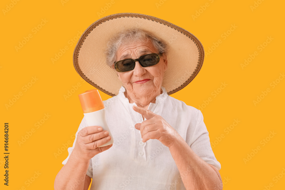 Senior woman pointing at sunscreen cream on orange background