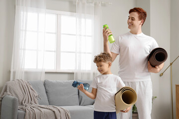 Wall Mural - Sporty young man with his little son and equipment at home