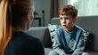 © The Little Hut - Child discussing his problems with a therapist Woman who works as a psychotherapist or school psychologist sitting on the sofa and talking to a little school boy Childrens psychology c : Generative AI