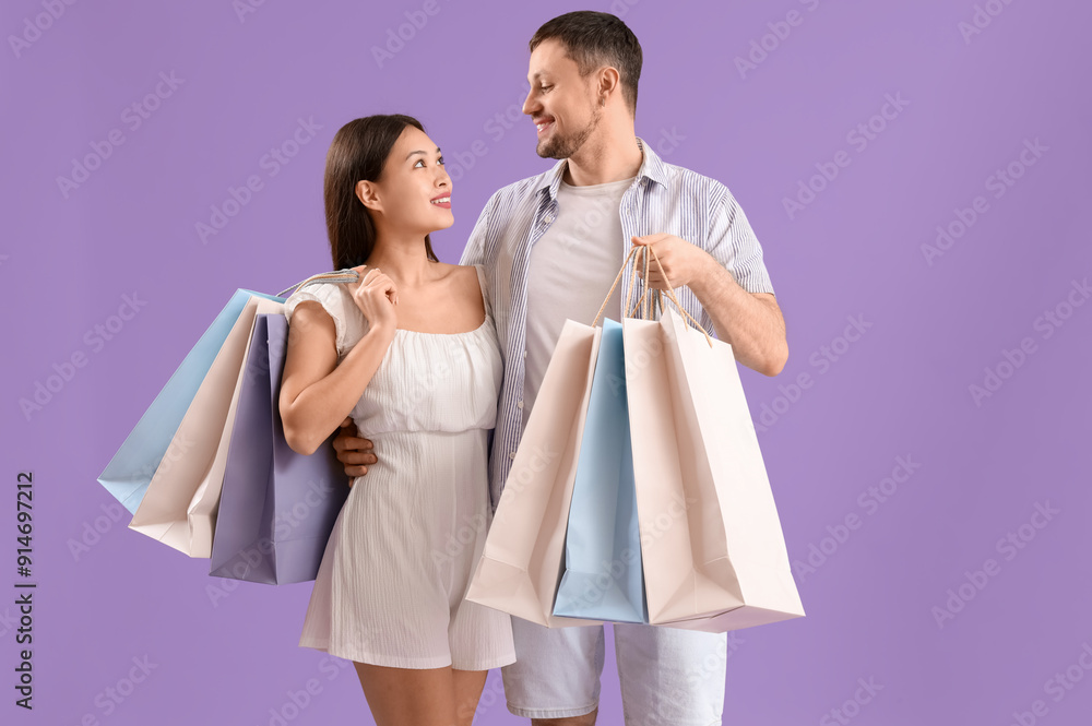 Young couple with shopping bags on lilac background