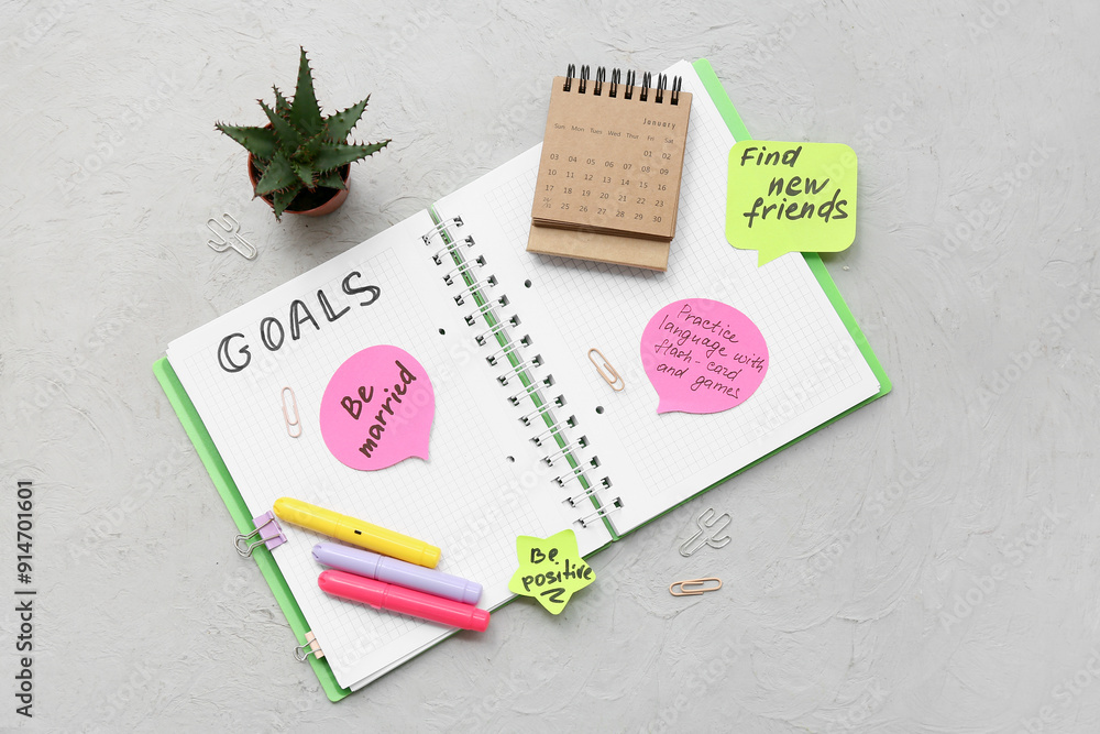Notebook with empty to do list, sticky notes and stationery on grey background. New year goals concept