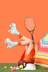 Sticker - Female legs in roller skates near umbrella and tennis balls on orange background. Travel concept