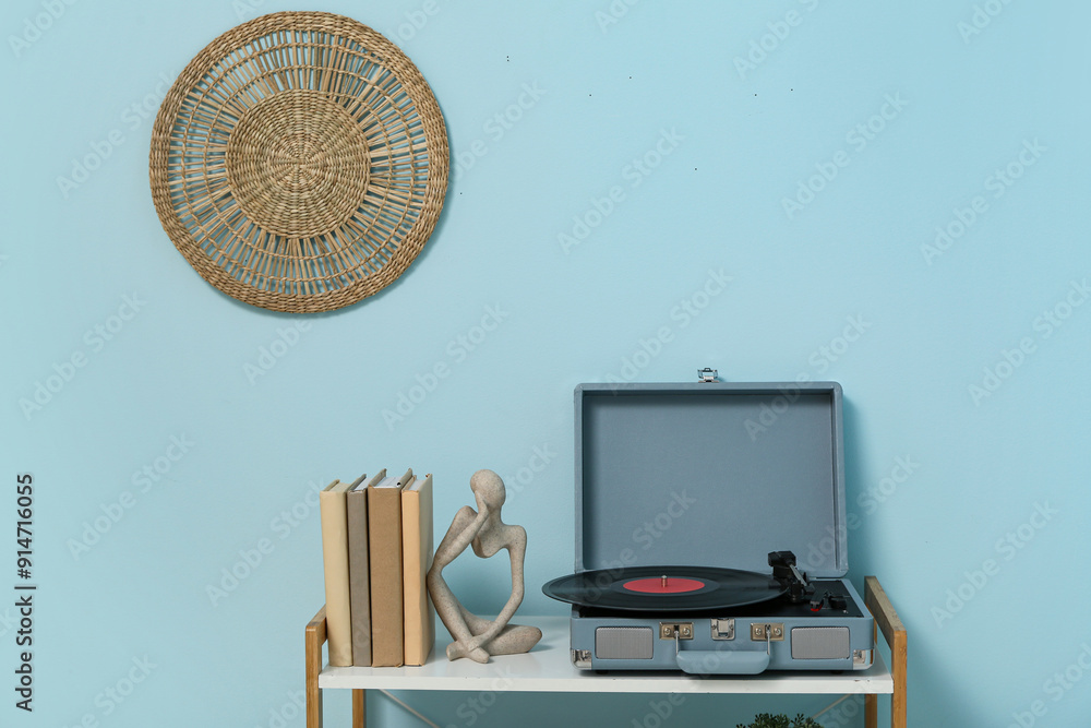 Record player with disk and home decor on shelving unit near blue wall in room