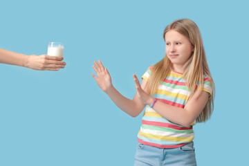 Sticker - Little girl refusing glass of milk on blue background