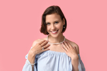 Wall Mural - Beautiful young happy woman wearing stylish pearl jewelry on pink background