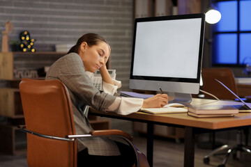 Wall Mural - Young tired woman working with modern computer and writing on notebook in office