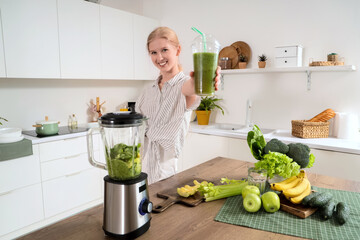 Wall Mural - Happy young woman with blender, ingredients and healthy smoothie in kitchen