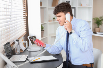 Poster - Male accountant working with calculator and talking on phone at workplace in office