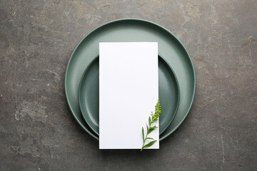 Canvas Print - Empty menu, plates and floral decor on grey table, top view. Mockup for design