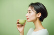 © nekokawaodori - 緑茶を飲む若いアジア人女性の横顔。緑色の背景。