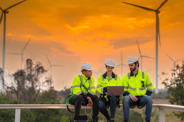 Team Engineers men and woman checking and inspecting on construction with sunset sky. people operation. Wind turbine for electrical of clean energy and environment. Industrial of sustainable.