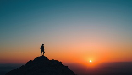 Wall Mural - Silhouette of a Person Standing on a Mountain Top at Sunset.
