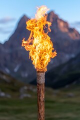 Canvas Print - Burning wooden torch against mountain backdrop