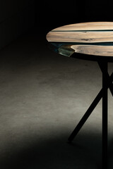 Wall Mural - Expensive vintage furniture. The table is covered with epoxy resin and varnished. Luxury quality wood processing. Wooden table on a dark background. A blue epoxy river in a round tree slab.