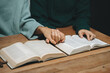 © Nuttapong punna - Group of Christians sit together and pray around a wooden table with blurred open Bible pages in their homeroom. Prayer for brothers, faith, hope,