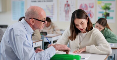 Poster - Man, teacher and girl at desk for education, question and help with information in classroom. Male tutor, student and discussion at table for shared knowledge, life science lesson and assistance