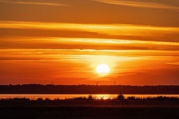 Canvas Print - Beautiful sunset by a lake with the sun and wind turbines