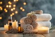 © robertuzhbt89 - A serene spa setting featuring neatly rolled towels, essential oils in amber bottles, and lit candles.