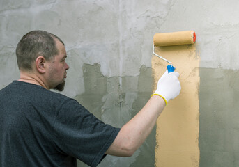 Wall Mural - A man is painting a wall with a roller