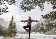 © Cavan Images - Woman does yoga pose in a snowy nature scene