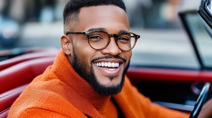 Poster - A man wearing glasses and a red sweater is smiling at the camera. He is sitting in a car and he is happy