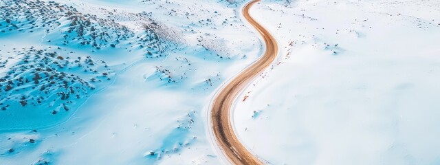 Wall Mural -  Abird's-eye perspective of a meandering path through a snowy expanse, bordered by evergreens in the distant horizon