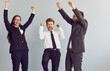 © Studio Romantic - Portrait of a group of business people in suits celebrating success in business or making a deal with hands in fist gesture like a winners isolated on a studio grey background. Team work concept.