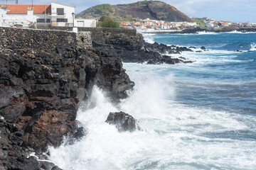 Atlantic Ocean waves crashing against volcanic rocks on the rugged coastline of Terceira Island, Azores, Portugal.