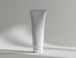 © pavlofox - Simple white cosmetic tube on a gray backdrop capturing light and shadow
