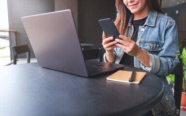 Wall Mural - Closeup image of a young woman using smart phone and laptop computer