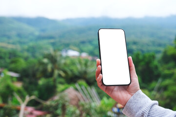 Mockup image of a woman holding mobile phone with blank desktop screen with mountain views