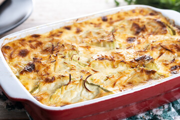 Casserole with cheese and gratin zucchini on wooden table