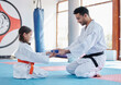 © peopleimages.com - Karate, promotion and student with blue belt for learning, training and kid practice taekwondo. Martial arts, teacher and people in class for reward, success and master giving girl child obi in gym