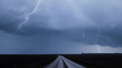 Wall Mural - A long road with a storm in the background. The sky is dark and the lightning is striking