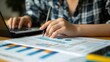 © yailek - Businesswoman analyzing financial report and using laptop