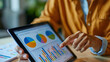 © yailek - Businesswoman analyzing graphs and charts on digital tablet screen