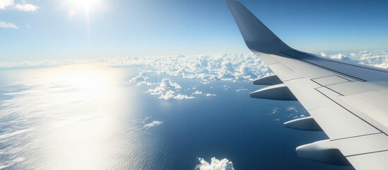 Wall Mural - wing of an airplane above the ocean with a blue sky and clouds. with copy space image. place for add