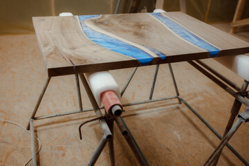 Wall Mural - Craft manufacturing of exclusive wooden tables. Workshop for the production of countertops with elements of epoxy resin. A dusty tabletop in a woodworking shop after sanding.