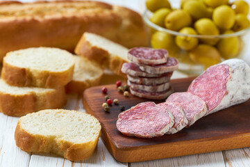 traditional Spanish salami fuet sausage with rosemary and baguet  on a cutting board close up.