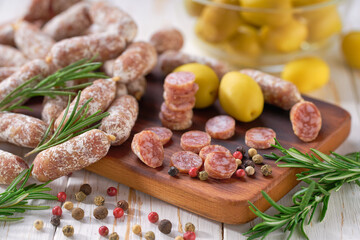 Wall Mural - chorizo mini, spicy pork fermented dry cured salami sausages with spices and olives  on a wooden table.