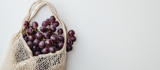 Fototapete - Eco friendly beige shopping bag featuring grapes on a white background String bag containing fruits Zero waste plastic free concept Copy space