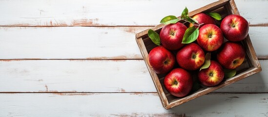 Poster - Red apples in a wooden box Organic red apples with leaves on a white wooden surface top view copyspace