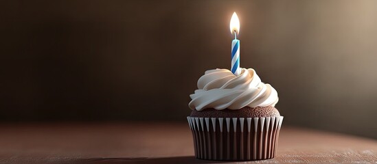 Poster - A brown and white cupcake topped with a burning blue and white striped birthday candle. with copy space image. Place for adding text or design