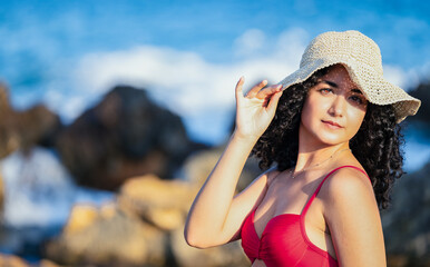 Pretty young girl on the seashore with beach hat