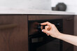 © brizmaker - Woman regulates the temperature of the oven on kitchen