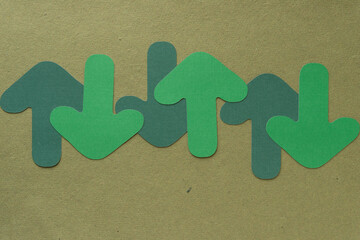 Poster - machine-cut green paper arrows pointing up and down on textured green paper