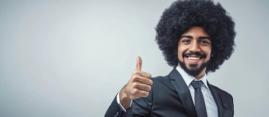 Funky businessman with a black curly afro wig is giving a thumbs up while pointing to the grey copy space on the right The smiling individual is suggesting or endorsing something positive Advertisemen