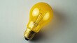 © MakoPoko - Flat lay of a yellow light bulb, providing a bright and innovative visual concept.