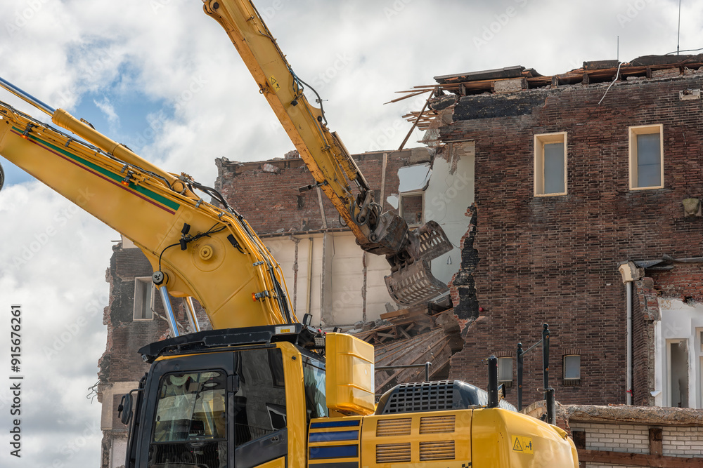 metal bucket of a demolition machine is busy demolishing a building