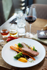 Wall Mural - Duck fillet with sweet potato cream, roasted carrots, kale, beet-port sauce on white plate. Grilled and roasted poultry closeup served on a table for lunch in modern cuisine gourmet restaurant.